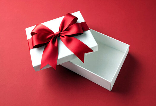 Beautiful white gift box with elegant red satin ribbon bow open on red background