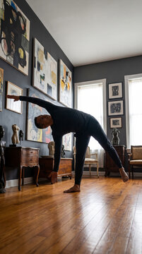 Skilled man stretches into a resolute side bend pose within an eclectic art-filled room