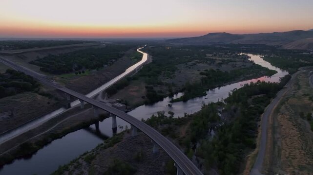 Aerial view of Lucky Peak Lake bridge spanning the river at sunset with surrounding hills and road infrastructure in Ada County, Idaho, United States.