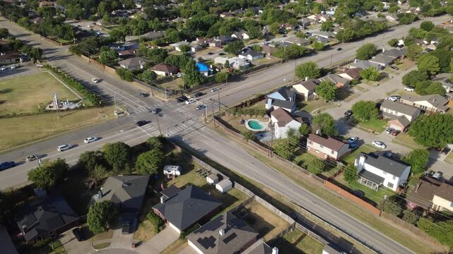 Multi lane intersection crosswalks connect East Sublett Road to Southeast Parkway thoroughfares. Pitched composite shingle roofs border tidy fenced backyard lawns, driveways, Arlington, Texas