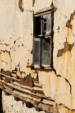 View of a weathered, cracked mud-plaster wall with exposed wooden laths and a rustic window frame in the historic village of Gostusa, Stara planina, Pirot District, Serbia.