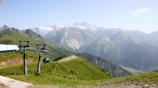 Scenic cable car glides lush valley with towering metal columns along scenic Grossglockner Alps Tyrol valley mountains. Panoramic view  sweeping alpine vistas stunning journey high above terrain
