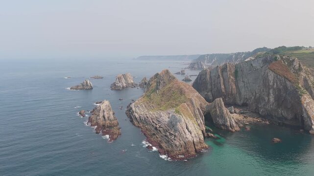 Aerial footage of the rugged coastline near El Peine del Mar in Cudillero, Spain, featuring dramatic sea cliffs, jagged rock formations, and turquoise waters.