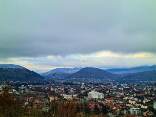 Fototapeta premium Town view surrounded by hills under cloudy sky