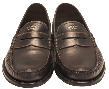 Classic black leather slip-on moccasin with the golden Prada logo screen-printed on the tongue.Milan - Italy,17 August 2026
