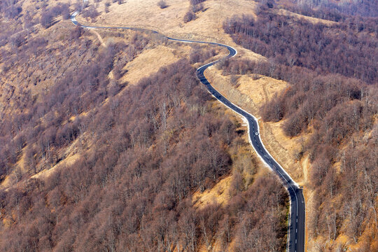View of the winding road through the Stara planina mountain range, surrounded by autumn forests and rugged terrain in Babin zub, Pirot District, Serbia.