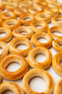 Golden bagels arranged in close-up pattern on light background. Ring-shaped bread, baked texture and warm crust create food imagery suited to bakery menus, packaging, advertising and retail.