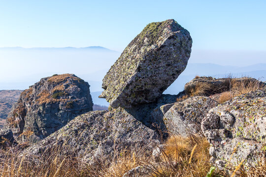 View of the distinctive rock formations of Stara planina surrounded by dry mountain grass and hazy distant peaks in Babin zub, Pirot District, Serbia.