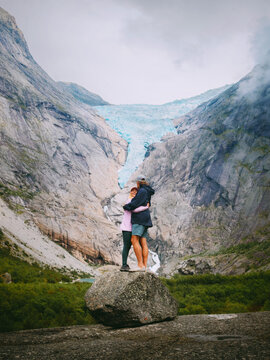 Couple in love hugging in mountains travel together romantic vacations tour in Norway adventure healthy lifestyle, family man and woman hiking enjoying Briksdalsbreen glacier view, bonding moments