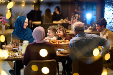 Fototapeta premium Multi Generational Muslim Family Enjoying Warm Dinner Together at Restaurant With Large Shared Platter