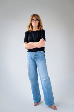 Full lenght studio portrait of a blond haired mature woman in casual clothes against isolated background