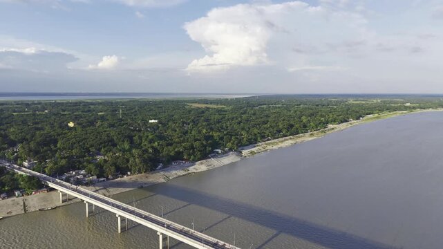 Aerial footage of Haripur Bridge crossing the Gorai River, with expansive water, green vegetation, and the opposite riverbank visible beyond the bridge.