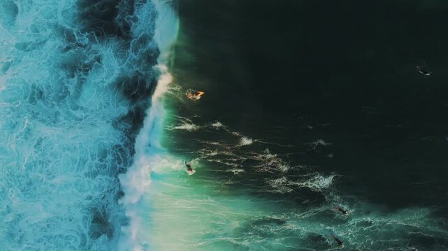 Breathtaking cinematic drone flight above surfers in ocean water below Jaran Hill Uluwatu &ndash; Spectacular crystal clear turquoise sea, surf lineup and dramatic coastal cliff in South Bali, 4k UHD