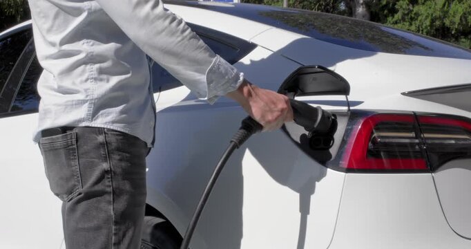 The driver connects the charging plug to an open socket on the electric vehicle. Preparing to charge the electric vehicle.