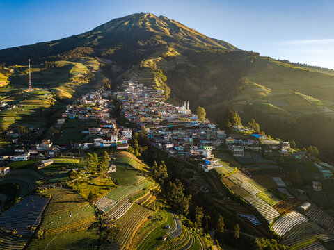 Aerial view of Nepal Van Java village nestled on the slopes of Mount Sumbing, surrounded by terraced vegetable fields and lush green hills in Kaliangkrik, Central Java, Indonesia.
