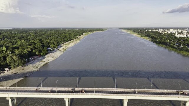 Aerial drone footage moving slowly from left to right with Haripur Bridge centered in the frame, revealing Kushtia city on one side and green riverside landscape along the Gorai River on the other.