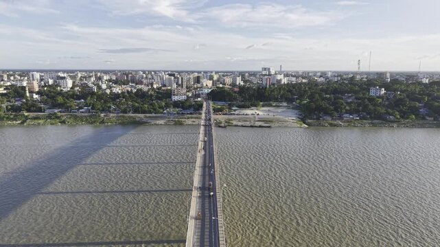Aerial drone footage approaching Haripur Bridge over the Gorai River, with vehicles and pedestrians crossing the bridge and Kushtia city visible beyond the riverbank.
