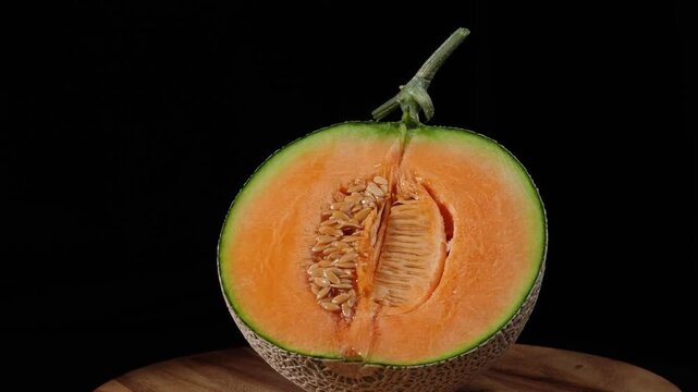 A half of cantaloupe melon a black background