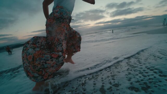 Intimate close-up of a floral sundress flowing in the sea breeze over rushing surf at coastal dusk, delicate fabric swirling, romantic, dreamy and feminine seaside mood.