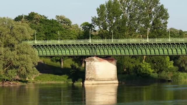 The historic Pont Canal bridge in Briare, France, spanning a calm river with lush green trees in the background, wide shot.