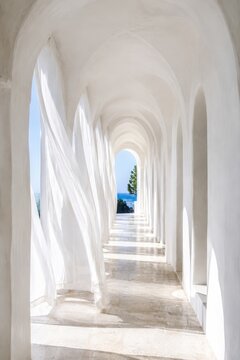White arched corridor with sheer curtains at seaside villa