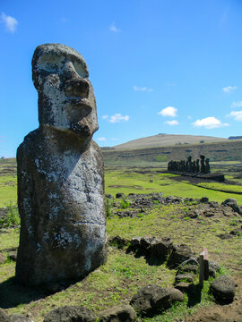 Vertical view of a moai on Easter Island with a group of statues in the background.