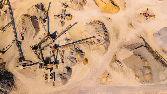 Top down view of conveyor belt system in sand extraction site. Aerial overhead layout of industrial sorters sand piles dirt paths and equipment in quarry zone.