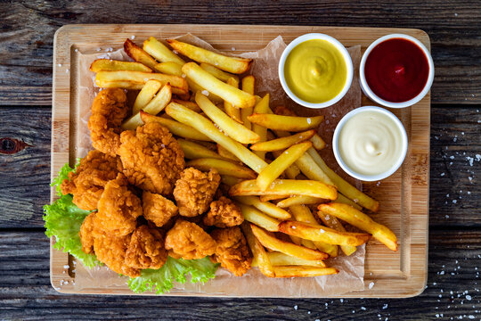 Breaded chicken nuggets with French fries and mayonnaise, ketchup, mustard on wooden table. Top view

