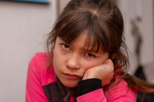 Thoughtful young girl resting her face on hand with bored expression