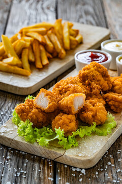 Breaded chicken nuggets with French fries and mayonnaise, ketchup, mustard on wooden table
