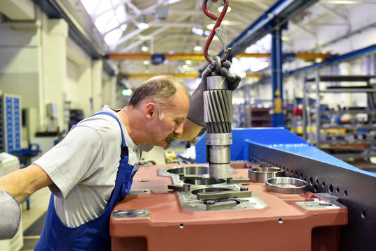 older worker in mechanical engineering - industrial factory for the production of steel gearboxes