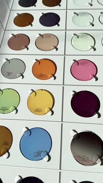 A selection of multicolored photochromic eyeglass lenses on a white base, as well as custom-made eyeglass lenses from an optical clinic or store. Anti-glare lenses