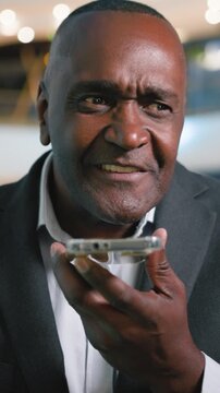 Excited smiling happy mature African American business man recording audio message with mobile phone easy command app businessman male specialist smile record voice mail communicate with smartphone