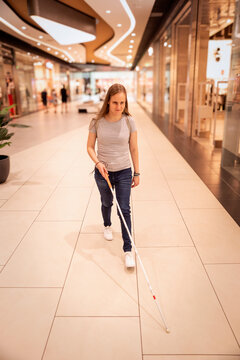 Blind woman with white cane walking in shopping mall