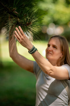 A blind or visually impaired woman exploring the pine needles in the park by touch.
