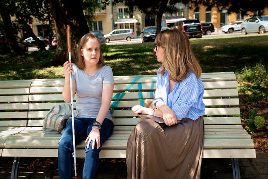 A woman with a disability and her female friend enjoying a summer day in a city park
