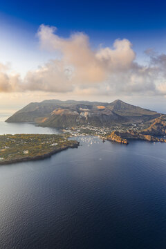 Aerial view of the volcanic island of Vulcano with its crater, surrounding blue sea, and coastal town in Lipari, Sicily, Italy.