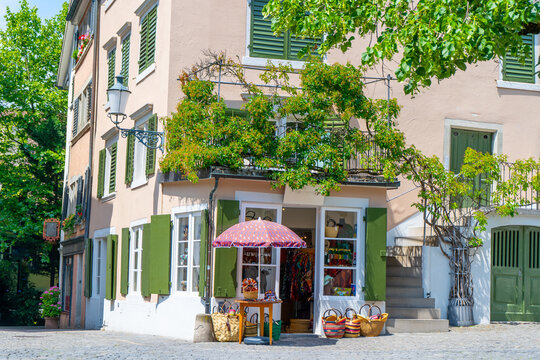 Cozy European flowers Shop with Green Shutters, Vine Balcony and Colorful Baskets on old Sunny Street in Zurich city