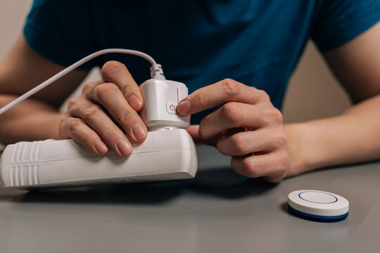 Cropped shot of person plugging a smart plug into a power strip and pressing its button, illustrating easy setup, remote control, energy saving home automation in a modern indoor setting.