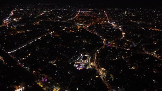 Aerial night view of an urban landscape in Syria featuring glowing city lights and illuminated streets.  Post-war Syrian cityscape and daily life at night.