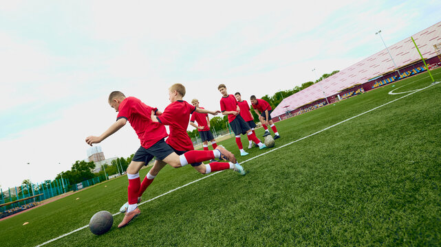 Teenage male football players moving ball forward during fast practice attack. Concept of offensive transition, counterattack training, spatial awareness.