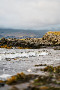 A small wave breaks on the rocky shoreline of Iceland's coast