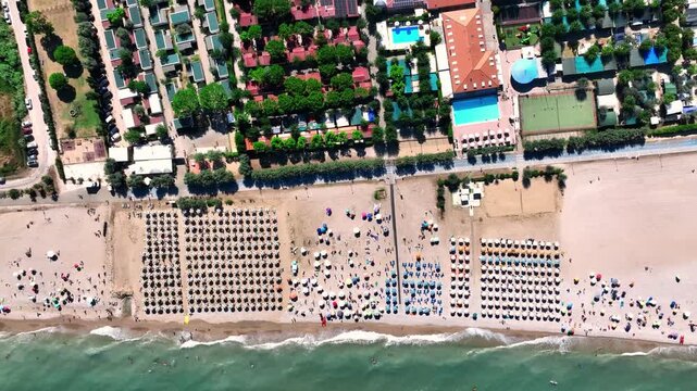 Aerial view of the beach resort in Porto San Giorgio with rows of umbrellas, swimming pools, and tourists on the sand in Porto San Giorgio, Marche, Italy.