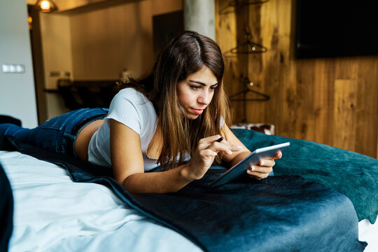 A woman using a tablet on a bed in a hotel room