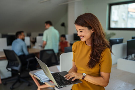 Smiling business woman using laptop in modern office