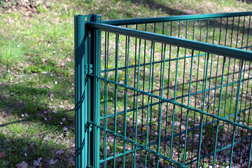 Clôture en panneaux de grillage rigide à double fil de couleur verte, installée sur des poteaux métalliques pour délimiter un espace extérieur. © CURIOS