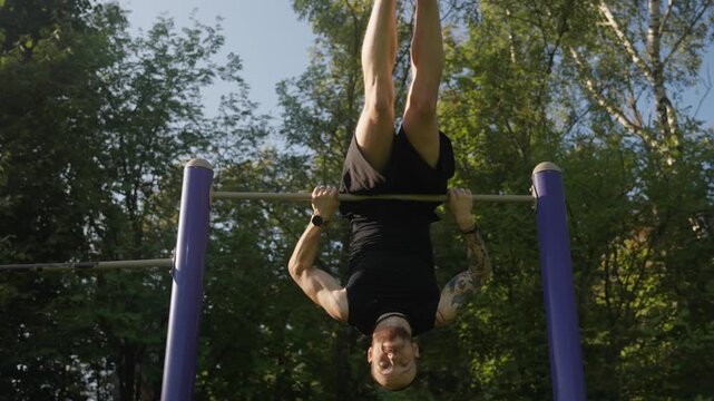 An athlete is doing a street workout on a pull-up bar, performing a pull-over