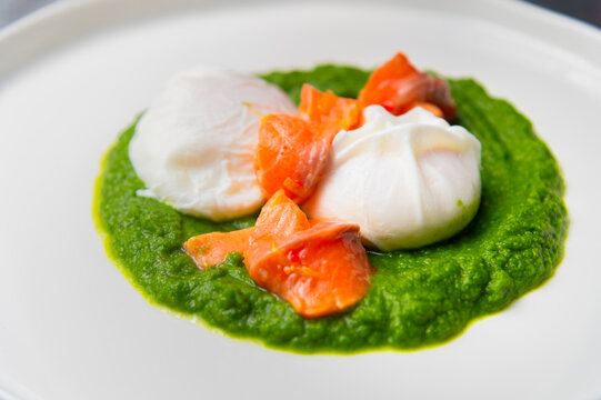 Poached eggs with salmon and spinach puree on a white plate