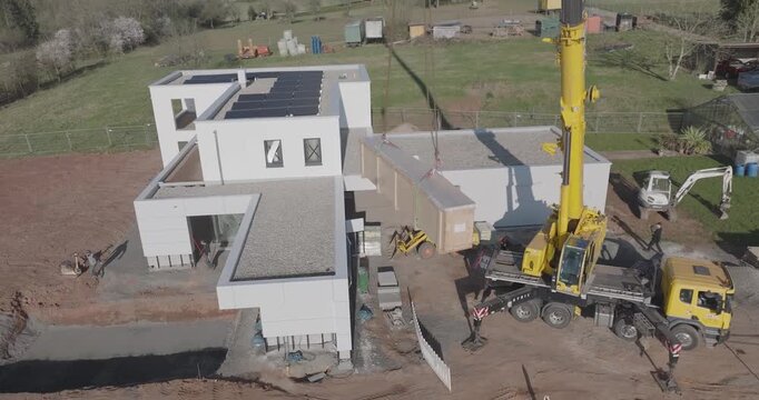 Mobile crane lifting timber element onto new house roof