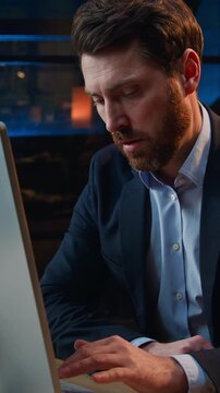 Bored unmotivated Caucasian business man working with boring computer work at night office at evening sad frustrated stressed overworked middle-aged businessman male employer feeling burnout deadline